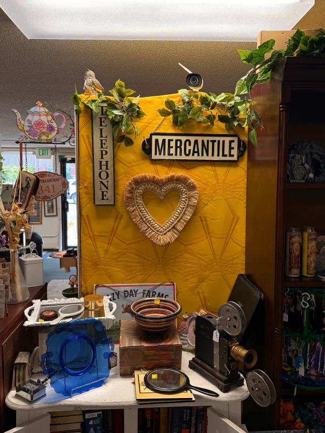Vintage mercantile sign, woven heart, and film projector displayed inside Unique Treasures.