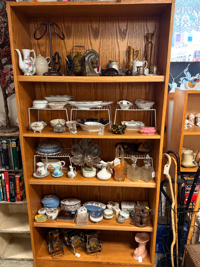 Teapots, dishes, and small antiques arranged together on store shelves.